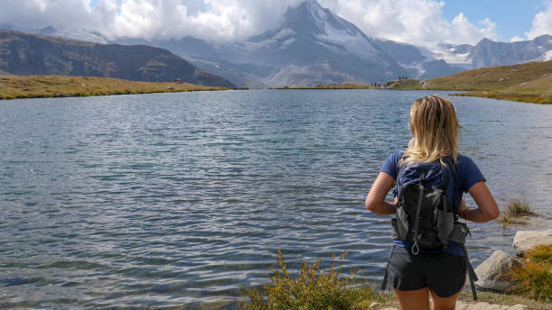 istock Young woman hikes along along water's edge 1212560338