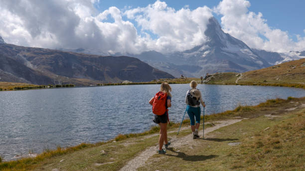istock Mother and daughter hike along along water's edge 1212560364