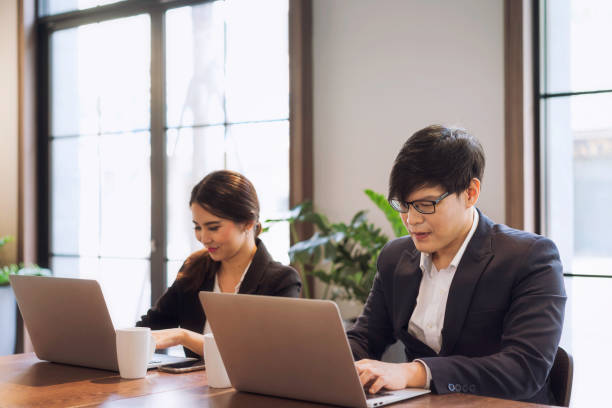 istock Co working space concept. Asian business looking in front of laptop while sitting at co-working space. young women and man working of new ideas in coffee shop. 1212560599