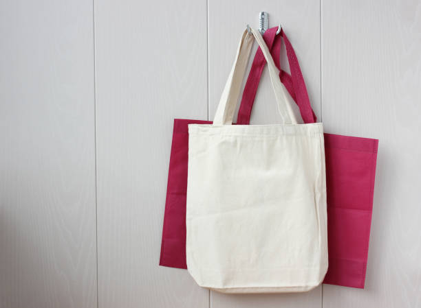 two bags of fabric hang on a hook on the light wall. without plastic. negative space for your text.