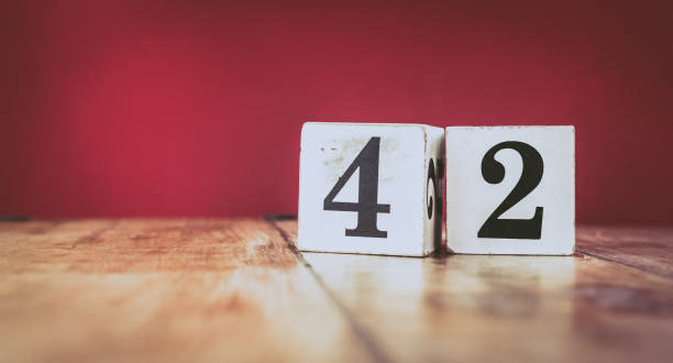 Number 42 on a vintage wooden table and dark maroon background - retro style white blocks Number 42 on a vintage wooden table and dark maroon background - retro style white blocks number 42 stock pictures, royalty-free photos & images