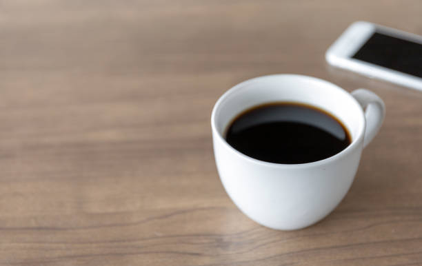 istock hot coffee cup on wooden table with soft-focus and over light in the background 1212562912