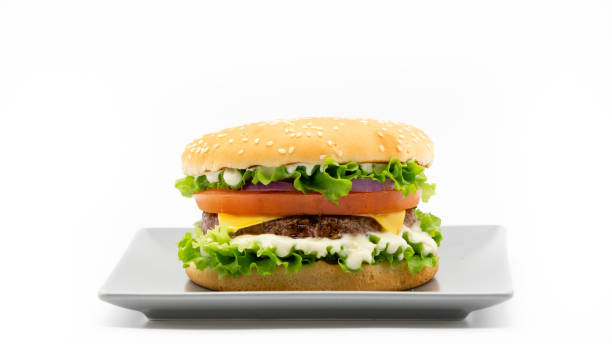 Burger on a plate. Hamburger, cheeseburger. Fast food Homemade burger. Hamburger. Cheeseburger with lettuce, sauce, meat, cheese, tomato, onion and bread on grey plate. Fast food. Lunch, dinner. White background, isolated. Copy space. Banner. cheeseburger photos stock pictures, royalty-free photos & images