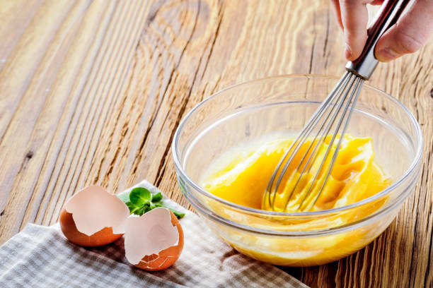 istock Woman whisking eggs. Wipped eggs in glass bowl with broken empty egg 1212565758