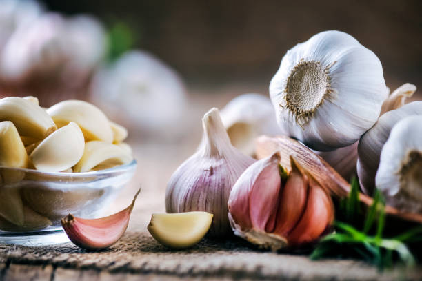 istock Garlic cloves on rustic table. Garlics in wooden bowl. 1212567061
