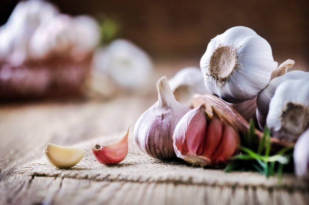 istock Garlic cloves on rustic table. Garlics in wooden bowl. 1212567069