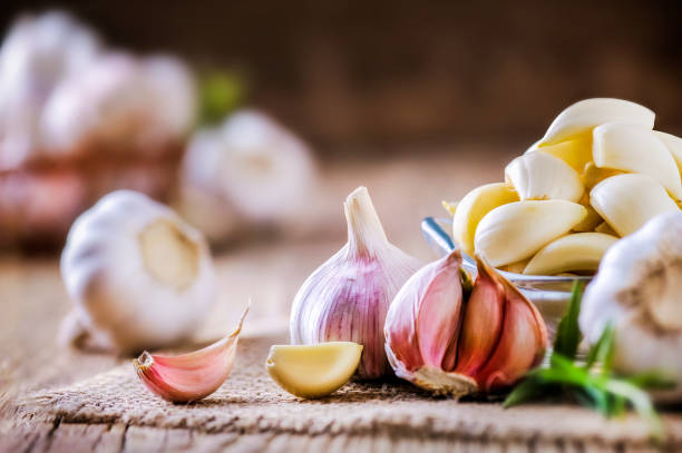 Garlic cloves on rustic table. Garlics in wooden bowl. stock photo