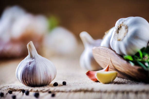 istock Garlic cloves on rustic table. Garlics in wooden bowl. 1212567079