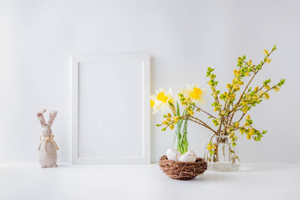 istock Home interior with easter decor. Mockup with a white frame and willow branches in a glass vase on a light background 1212568160