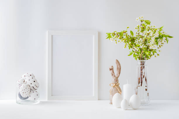istock Home interior with easter decor. Mockup with a white frame and spring flowers in a vases on a light background 1212568178