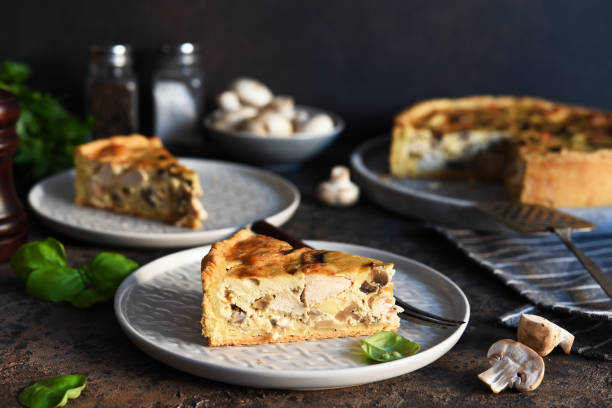 istock Tart slice on the kitchen table. Traditional quiche with chicken, mushrooms and cheese on a dark concrete background. 1212568193
