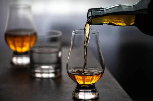 Pouring in tulip-shaped tasting glass Scotch single malt or blended whisky and glas of water