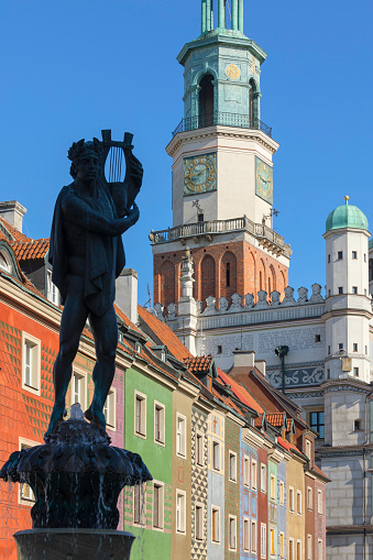 Sculpture of the Apollo fountain (replica of the original fountain) in front of historical townhouses and the town hall in Poznan, Poland.