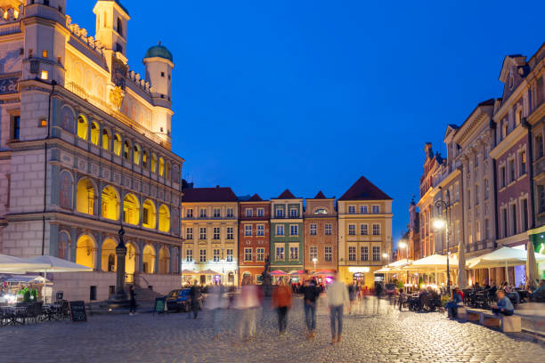 People out walking in the evening in the old town of Poznan. On the left is the historical town hall with origins from the 16th century.