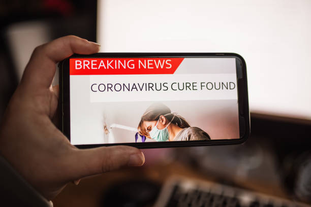 Coronavirus on the media - Cure found A mobile phone screen showing news about a coronavirus vaccine found research foundation stock pictures, royalty-free photos & images