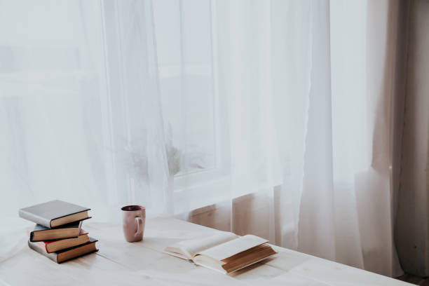 istock table with books and a mug at the window 1212570483