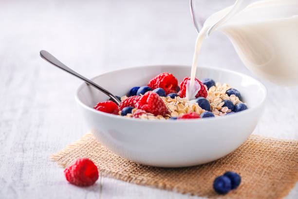 verter leche fresca en copos de avena - bran flakes fotografías e imágenes de stock