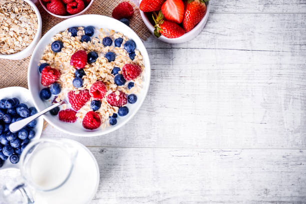 istock Top view on oat flakes with milk and forest fruit. 1212572236