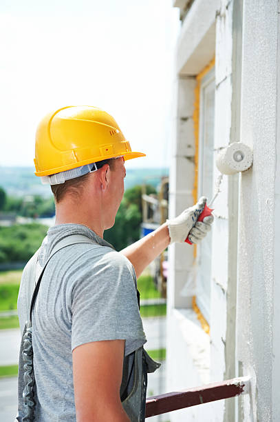 builder facade painter worker Young painting facade builder worker with roller at thermal insulation works steeplejack stock pictures, royalty-free photos & images