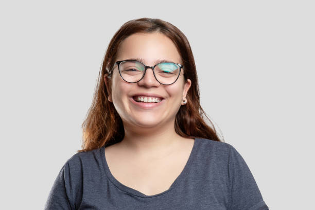 Portrait of cheerful young woman with glasses over gray background stock photo