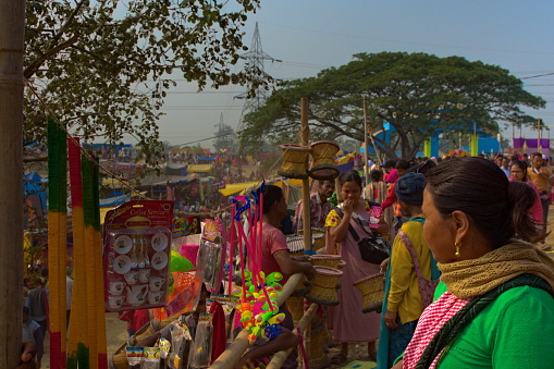Dayang Belguri, Morigaon, Assam, India-January 18, 2020: A woman checks out items for sale at Jonbeel Mela. This Mela is a unique fair where the barter system still exists.