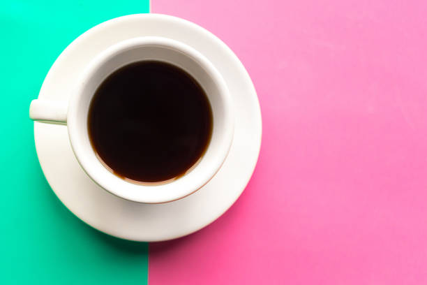 istock Coffee cup on green and pink pastel background. Top view. Minimal concept 1212577565