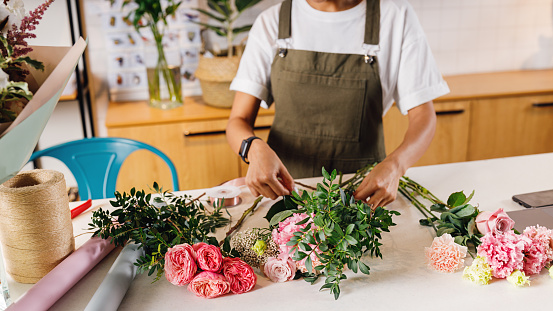 Unrecognizable woman florist making bouquet with flowers on counter