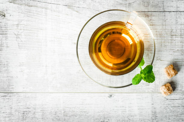 istock Top view of green tea with mint leaf and two brown sugar cubes. 1212580889
