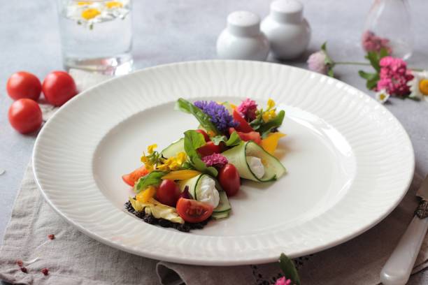 istock Colorful vegetable salad decorated with flowers on a white plate, light grey stone background. Healthy spring or summer lunch. 1212581672