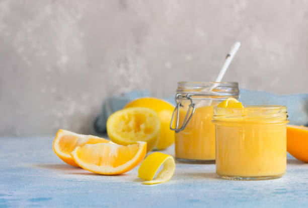 istock Homemade lemon curd or custard and fresh lemons on a light blue stone background. Selective focus. 1212581974
