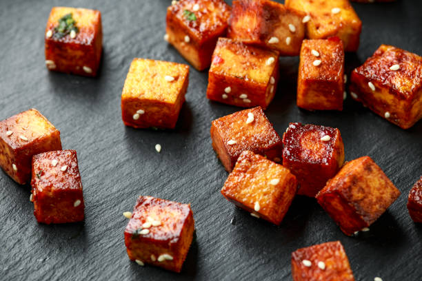 Fried Tofu with chopstick and sesame seeds on rustic stone board Fried Tofu with chopstick and sesame seeds on rustic stone board. tofu stock pictures, royalty-free photos & images