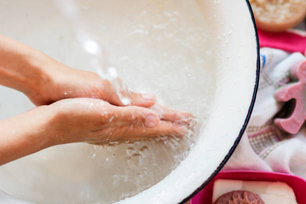 istock Child’s hands under white bowl with water upon water stream 1212582136