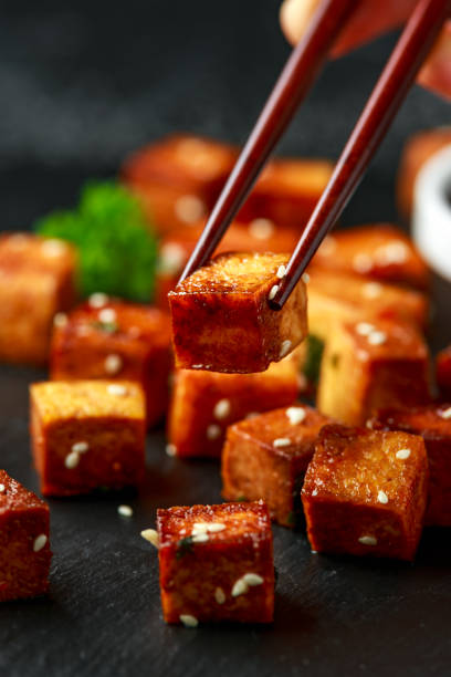 istock Fried Tofu with chopstick and sesame seeds on rustic stone board 1212582164