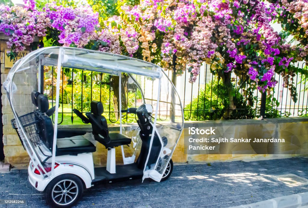 A parked eletric tricycle on the side of a wall and fence covered with beautiful flowers in the Prince Island, Turkey. Beauty Stock Photo