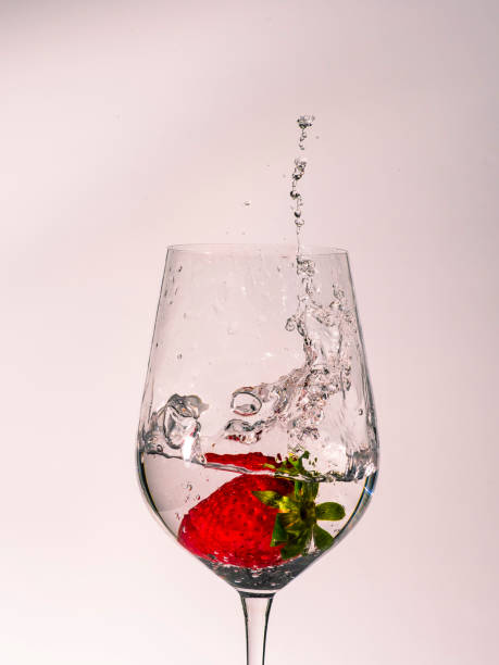 Cup with water falling from a strawberry and splashing out of the cup