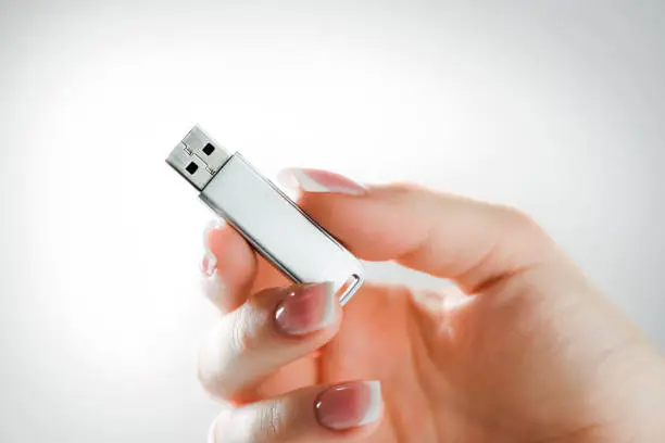 Photo of Woman hand holding silver usb in finger with beatiful nails.