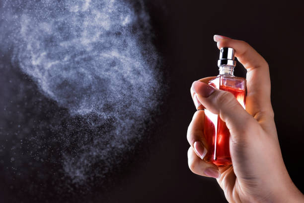istock Hand holding perfume spray on dark background. 1212587944