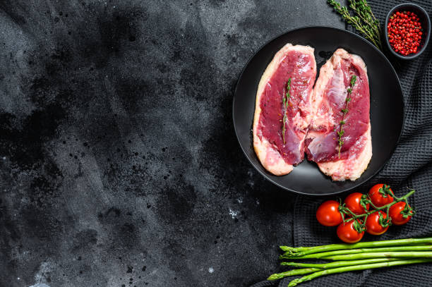istock Raw duck breast meat in a plate. Black background. Top view. Copy space 1212590650