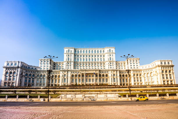 Palace of Parliament, Bucharest A yellow taxi passing by the Palace of Parliament in Bucharest city on Sunday. parliament palace in bucharest romania the largest building in europe stock pictures, royalty-free photos & images