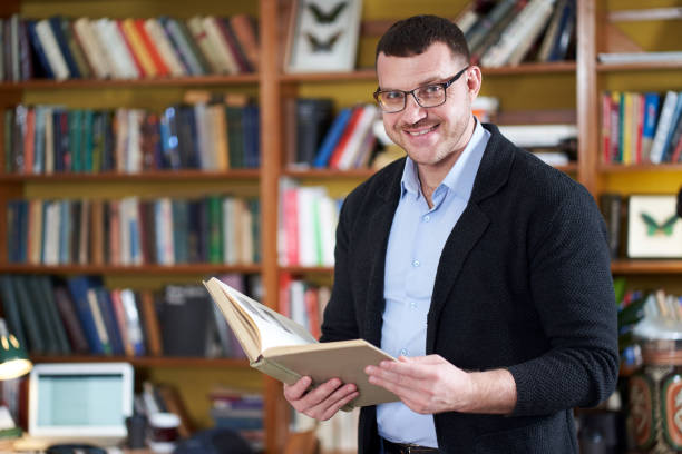 istock Man reading book in college library many books on a background 1212591765