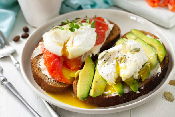 istock Morning breakfast close-up. Poached egg boiled sandwich with avocado, salmon and coffee on a wooden table. 1212594096
