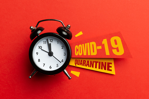 Background for Coronavirus. Alarm clock and colour papers on the red background.