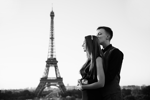 From Paris with love. Beautiful couple embracing near the Eiffel tower. Romantic date, honeymoon in France