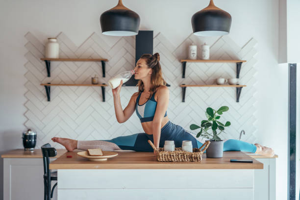 fit woman in split position on the kitchen table having breakfast. - the splits ethnic women exercising imagens e fotografias de stock