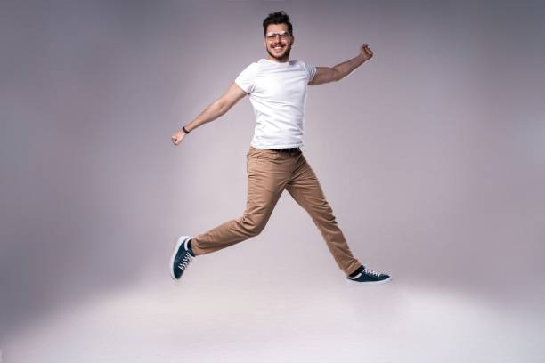 istock handsome man casual dressed celebrating and jumping on gray background 1212599635