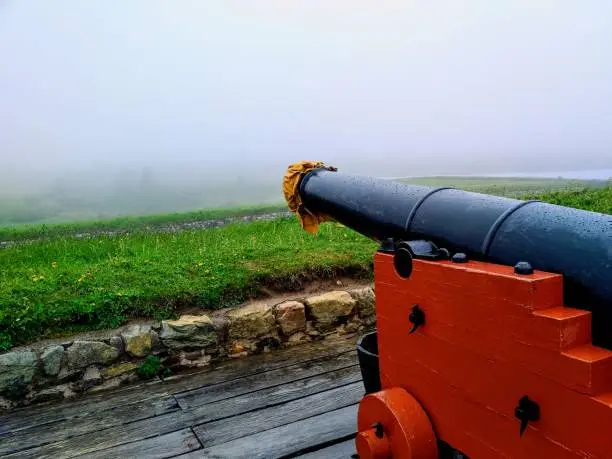 A French cannon points through the fog toward the Port at the Fortress of Louisbourg National Historic Site of Canada on Cape Breton Island in Nova Scotia.