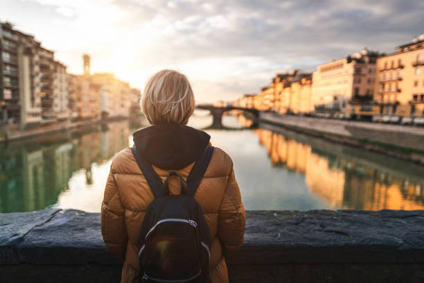 istock Tourist looking at Arno river from Ponte Vecchio in Florence 1212608370