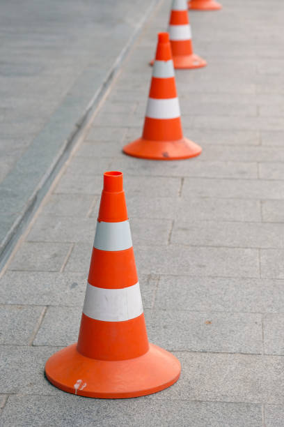 istock Several road cones on a square gray tile. Orange cones with white stripes. 1212609470