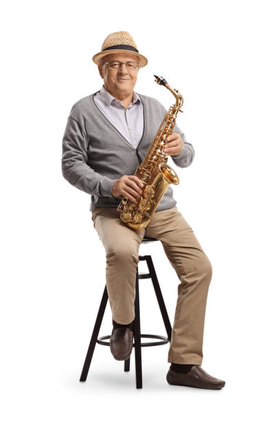 istock Elderly man sitting on a chair and holding a saxophone 1212611071