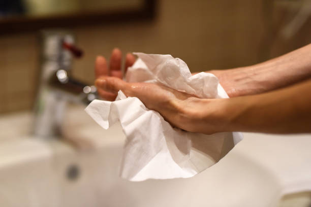 drying hands with paper towel Female hands using paper towel after washing, as a protection against viruses paper towel stock pictures, royalty-free photos & images